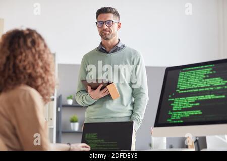 Mature businessman with tablet pc discussing online presentation with her colleague at office Stock Photo