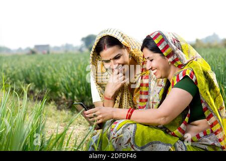 Two happy rural women using phone on agricultural field Stock Photo