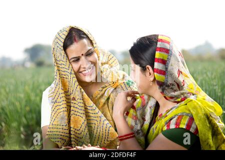 Two happy indian rural women talking on agricultural field Stock Photo