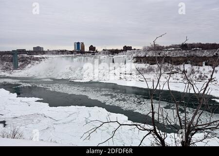 Looking across to Bridal Veil Falls and the USA from the Canadian side of Niagara Falls in winter after snow fall. Chunks of ice float along the river. Stock Photo