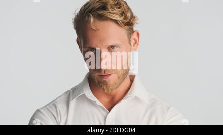 Young handsome bearded businessman in shirt looking serious on camera isolated on white background. Confident man in shirt Stock Photo