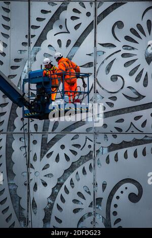 Glasgow, Scotland, UK. 4th Dec, 2020. Pictured: Workmen in PPE high viz orange seen on a cherry picker doing the finishing touches to the M8 Tower - a 131ft high stainless steel structure adorned with the teardrop paisley pattern shape, showcasing a giant electronic advertising display board above the White Cart Viaduct, which will showcase adverts to traffic in north directions. The structure cost more than a million pounds, being funded by Wildstone, the UK's largest outdoor advertising firm. Credit: Colin Fisher/Alamy Live News Stock Photo