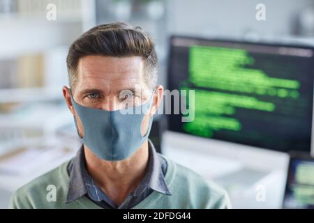 Portrait of young man in protective mask looking at camera while working at office Stock Photo