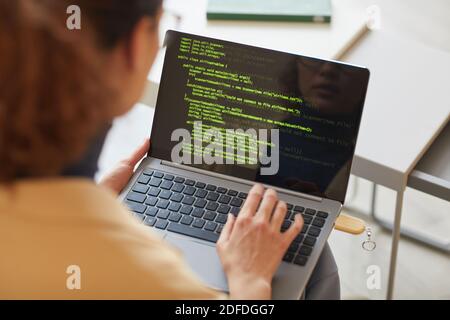 Rear view of female software programmer typing codes on laptop working with new software Stock Photo