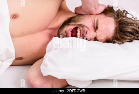 Tips on how to wake up feeling fresh and energetic. Morning routine tips to feel good all day. How to get up in morning feeling fresh. Late morning overslept. Man handsome guy lay in bed in morning. Stock Photo