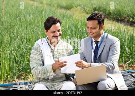 Farmer with businessman using laptop on agriculture field Stock Photo