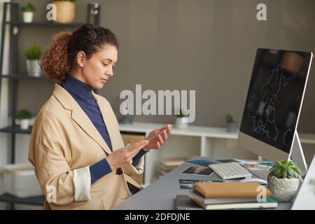 Serious female designer working with photos at her workplace with computer monitor on it at office Stock Photo