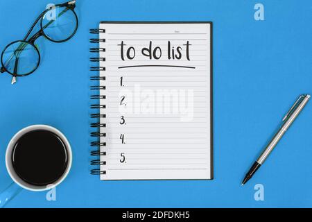 Overhead View of To Do List on Notepad Over Blue Background Stock Photo