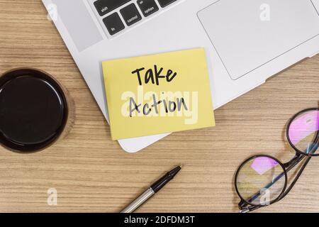 Overhead View of Take Action. Sticky Note and Laptop on Wooden Work Desk Stock Photo