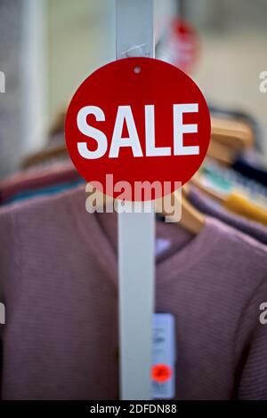 small red sign with white print SALE on a clothes rack Stock Photo