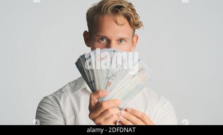Portrait of young handsome bearded businessman looking confident showing wad of money on camera isolated on white background Stock Photo