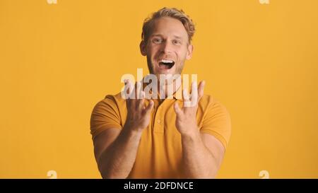 Young excited bearded man emotionally rejoicing on camera isolated on yellow background. Overjoyed expression Stock Photo