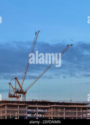 Construction cranes over a building under construction symbolize the construction boom in urban areas and urbanization with the population shift from Stock Photo