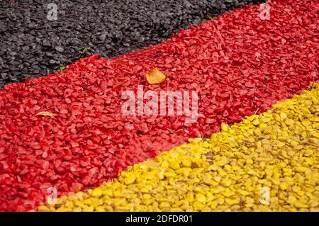 Fine gravel painted in dark grey, red and yellow Stock Photo