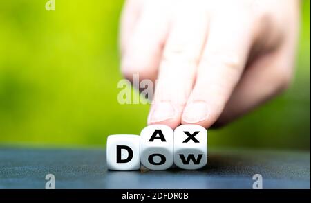 Hand turns dice and changes the abbreviation "DOW" to "DAX". Stock Photo