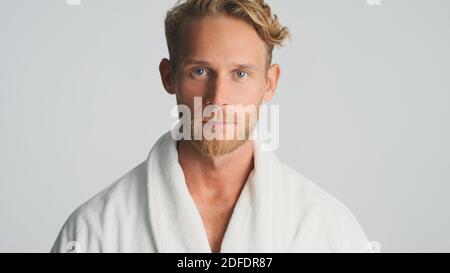 Handsome bearded man in bathrobe intently looking in camera isolated on white background Stock Photo