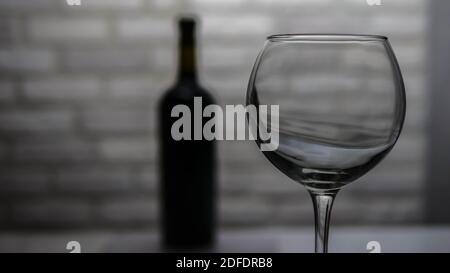 Empty wine glass on a brick wall background, wine bottle with glass. Stock Photo