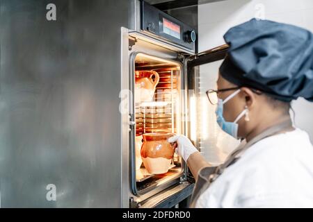 cook putting dishes in the oven Stock Photo
