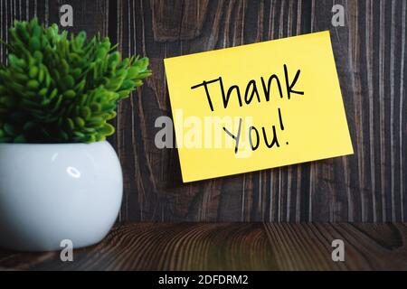 Thank You on Sticky Note Against Wooden Wall Stock Photo