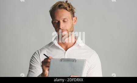 Handsome concentrated bearded businessman in shirt intently working with documents over white background. Business concept Stock Photo