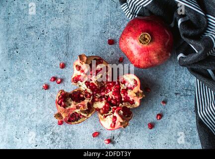 Overhead view of ripe pomegranate fruit and seeds on cement counter. Stock Photo