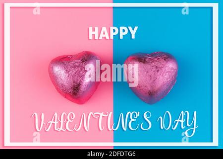 Concept of Valentine's Day and LGBT relationships. Two heart-shaped chocolates in a pink wrapper. The background is divided in half into pink and blue Stock Photo