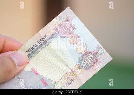 Hand holding Currency of the United Arab Emirates (UAE) - Close up of a purple five hundred Dirham note  on a blurred background. Stock Photo