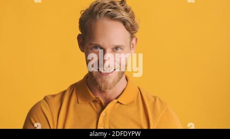 Handsome bearded man looking joyful posing on camera isolated on yellow background Stock Photo
