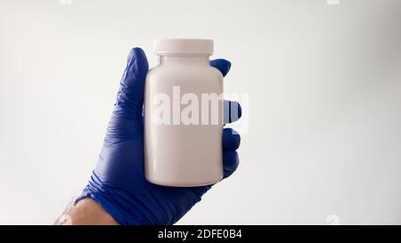 Male hand holds a white jar. Medical medicines.Place for text,name of pills. Stock Photo