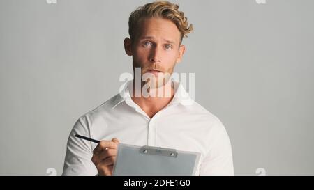Attractive bearded businessman in shirt intently looking in camera working with documents isolated on white background Stock Photo