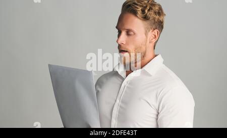 Young bearded businessman in shirt reading document papers working on new project over white background Stock Photo