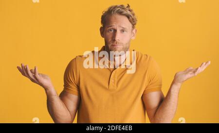 Doubtful bearded man throwing up hands showing I don't know expression on camera over colorful background Stock Photo