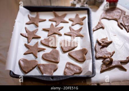 Raw gingerbread cut out stars, hearts on baking sheet Stock Photo