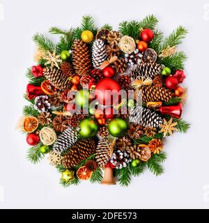 Vivid christmas wreath with fir branches, pine cones and rustic ornaments. Christmas decoration with baubles, jingle bells and dried orange slices. Stock Photo