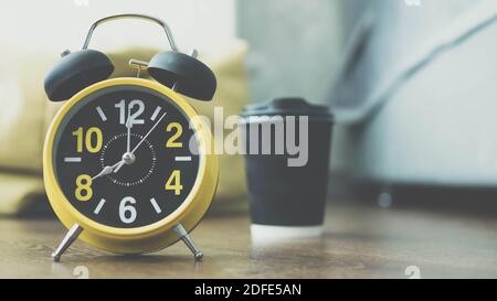 Beautiful retro clock with coffee in the background,a plastic glass of cappuccino,ammerecano lies on the parquet floor,aromatic morning coffee. Stock Photo