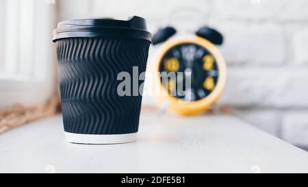 A glass of cappuccino,black coffee on a bar counter,in a cafe showcase,in the background a clock with an alarm clock,against a brick wall. Stock Photo