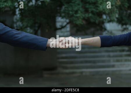 A closeup shot of a stylish couple reaching out and holding hands Stock Photo