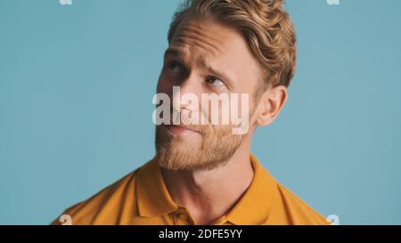 Attractive bearded man looking thoughtful posing on camera isolated on blue background Stock Photo