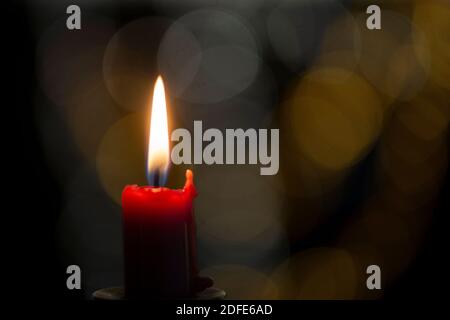 Burning candle on black background with bokeh. Christian Christmas concept. Stock Photo