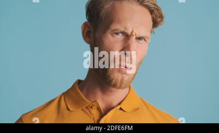 Young bearded man unpleasantly looking in camera over colorful background. Disgusted expression Stock Photo