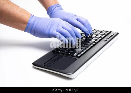 Gloved hands typing on computer keyboard Stock Photo