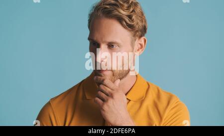 Young handsome bearded man looking thoughtful on camera over colorful background. Thinking expression Stock Photo
