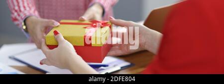 Businesswoman gives gift to colleague at workplace. Stock Photo