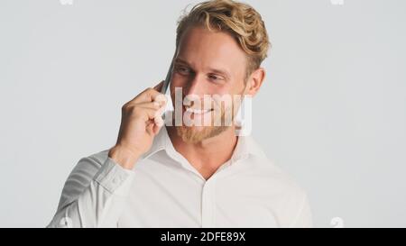 Handsome smiling bearded man in shirt discussing new business project talking on smartphone isolated on white background. Modern technology Stock Photo