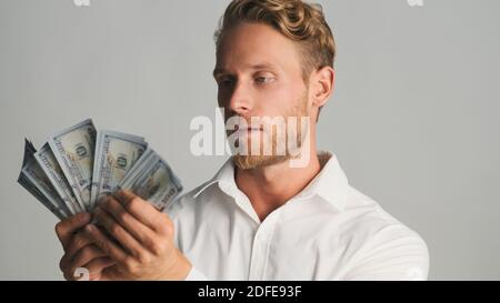 Handsome bearded businessman looking serious posing with money on camera over white background Stock Photo