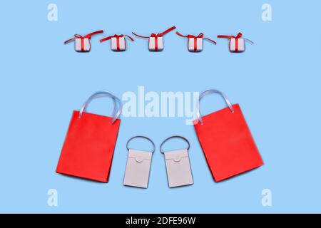 Shopping bags, two red large and two white small, lined up in an arc at the bottom. An even horizontal row of choice from white gift boxes with a red Stock Photo