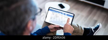 Man Using Tablet Computer Checking Bank Statement Online Stock Photo