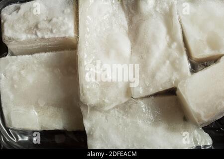 Close-up of the texture of frozen cod fillets wrapped in a plastic container. Food and fish. Stock Photo