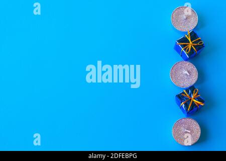 candles and gift boxes on blue background, christmas minimalistic holiday background, flat layout. Stock Photo