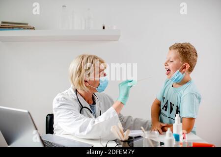 Doctor taking a sample from a boy's throat using a cotton swab Stock Photo